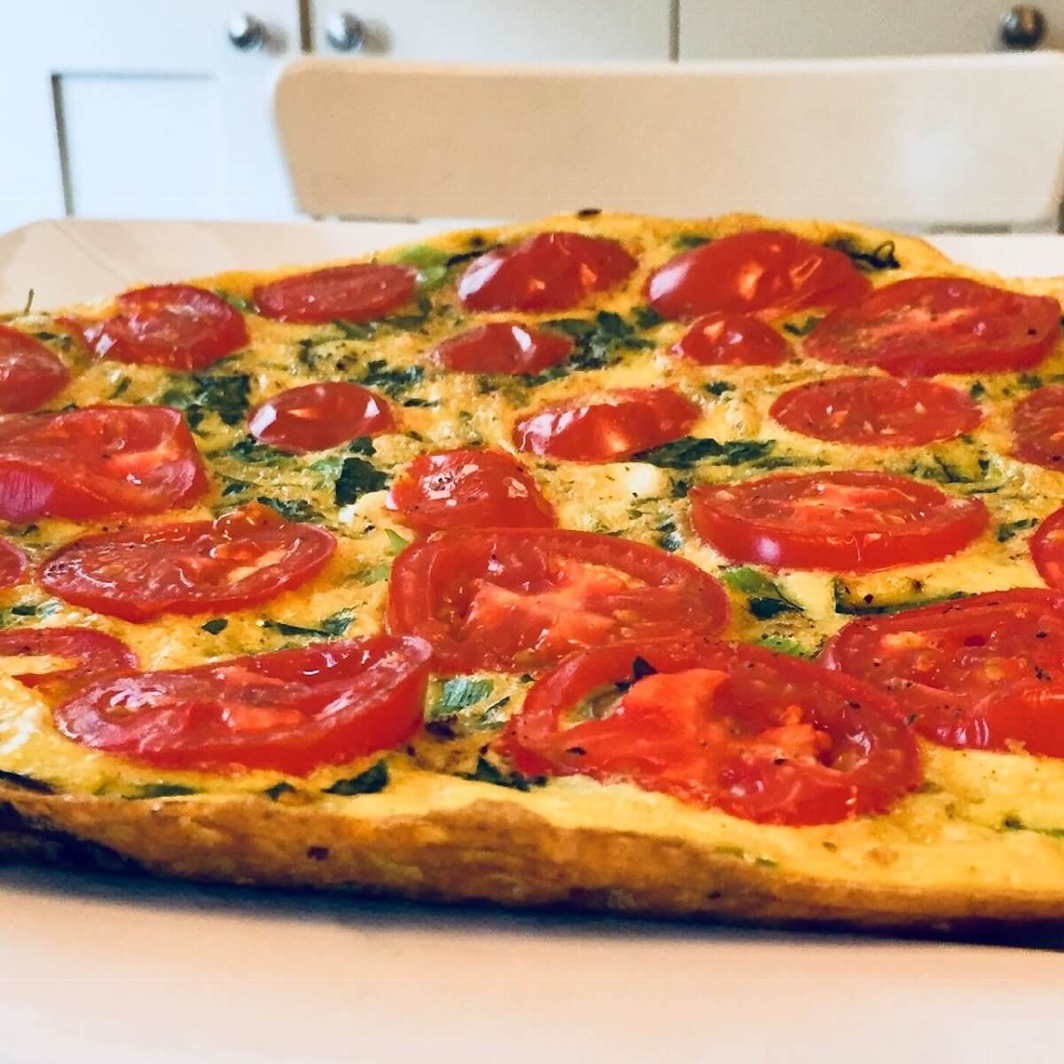 A large, round, dairy free frittata on a white plate.