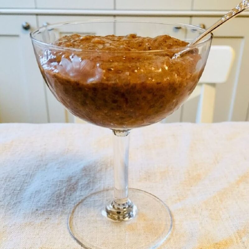 Gingerbread pudding in a glass dish with cupboards in the background.