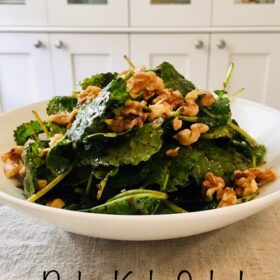 A big bowl of salad with walnuts sprinkled on top.