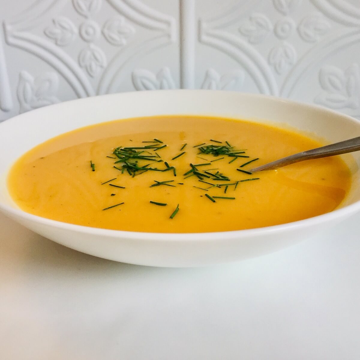 A white bowl of paleo butternut squash soup.