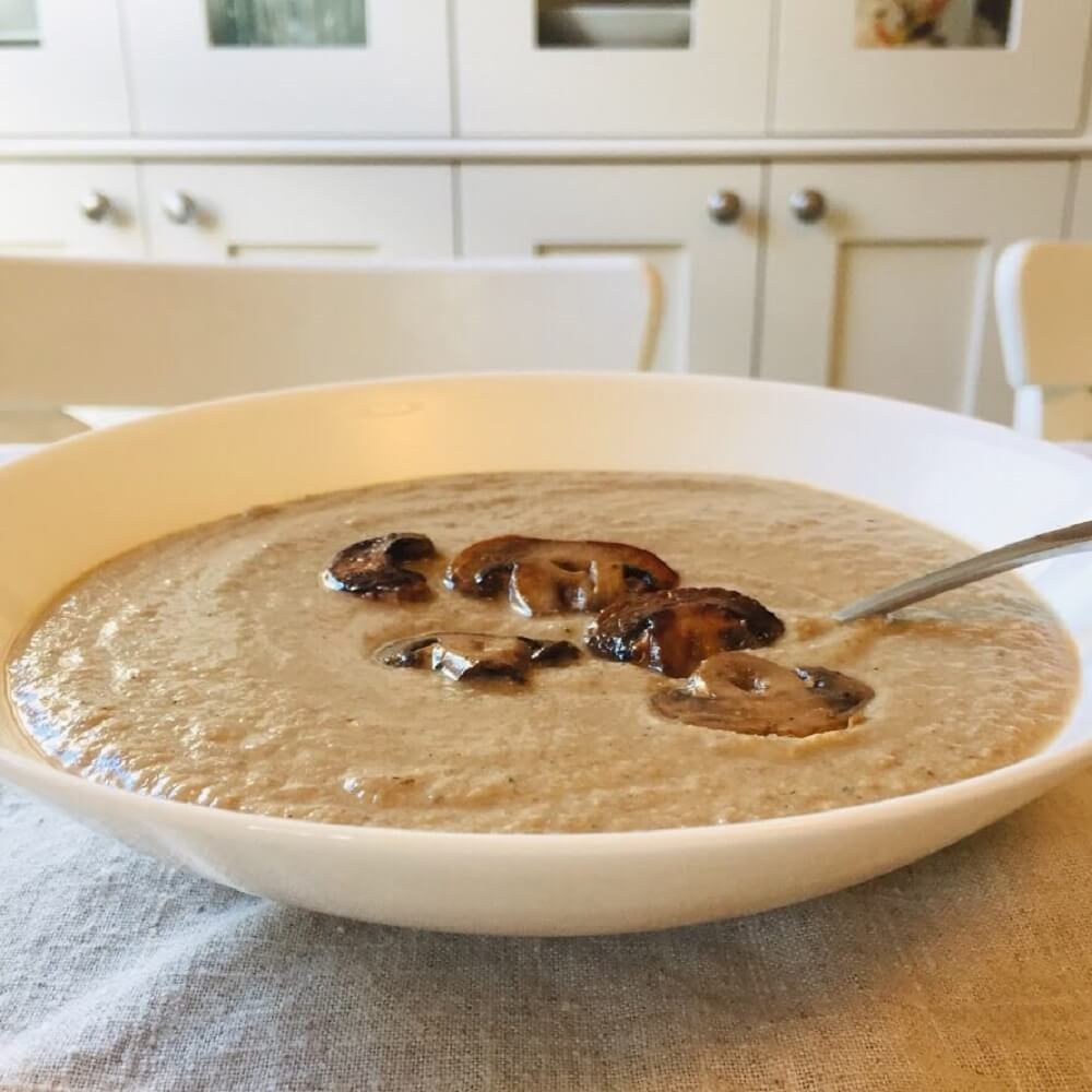 dairy-free cream of mushroom soup in a white bowl with a spoon.