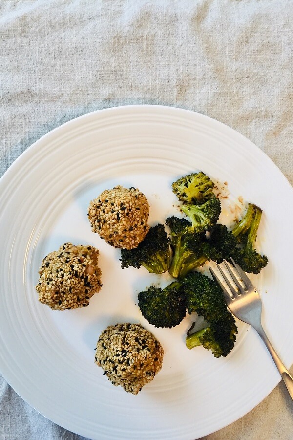 Paleo chicken meatballs and broccoli on a white plate with a fork.