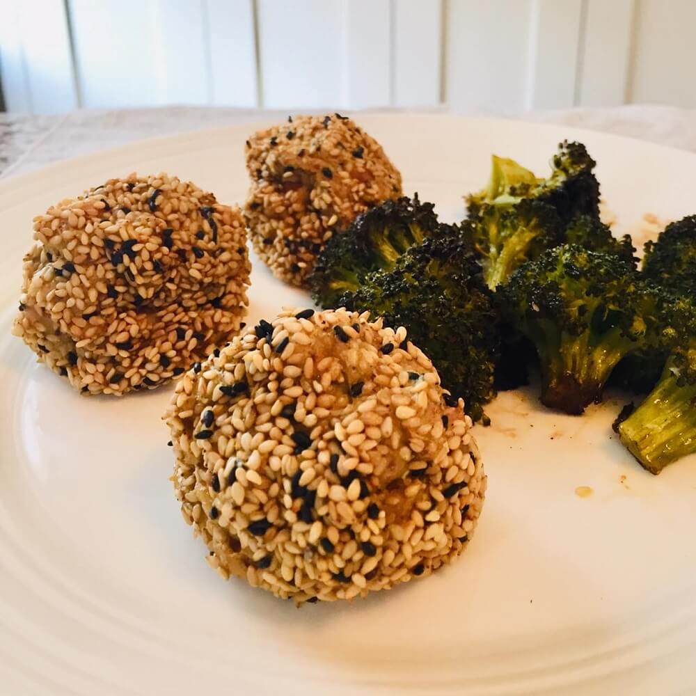 Paleo chicken meatballs on a white plate with some broccoli.