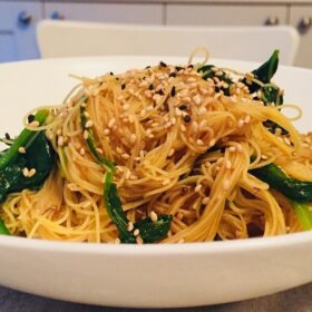 A bowl of noodles with cupboards in the background.