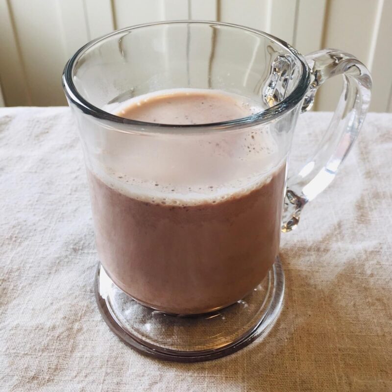 A glass mug of refined sugar-free hot cocoa on a linen napkin.
