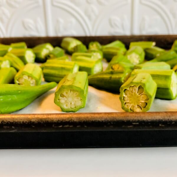 Okra on a parchment paper lined baking tray.