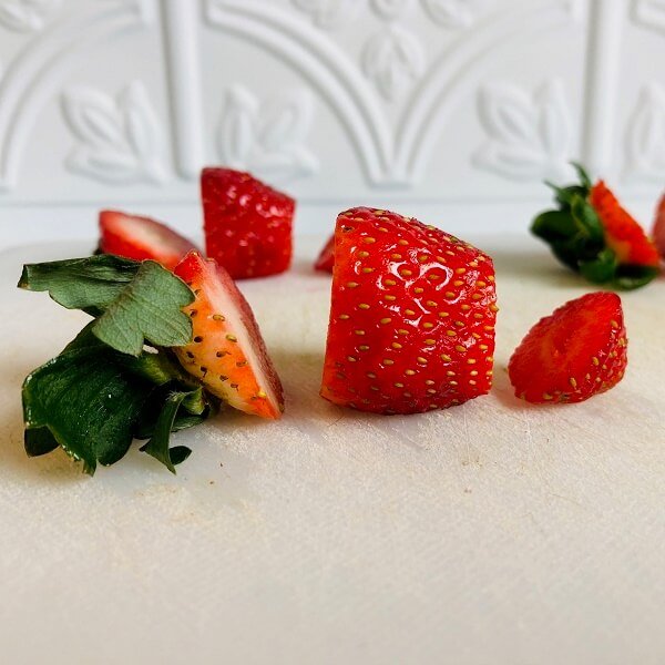 Strawberries sliced on a cutting board.