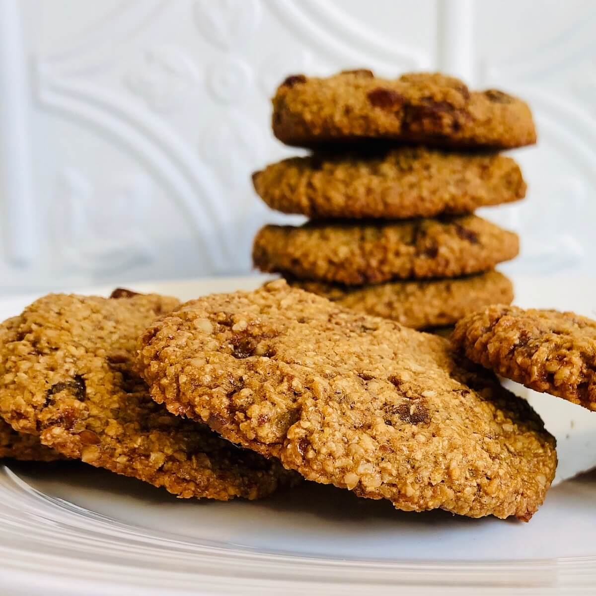 A white plate piled with vegan oat flour cookies against a white background.