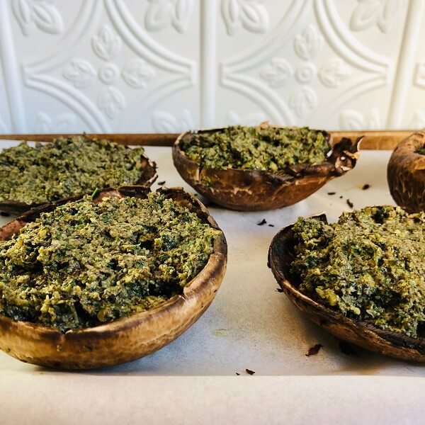 Mushrooms filled with stuffing on a baking tray.