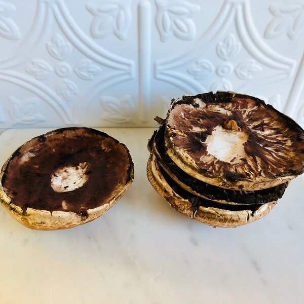 Mushrooms on a cutting board with gills and stalks removed.