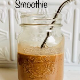 A jar of smoothie with a metal straw in it.