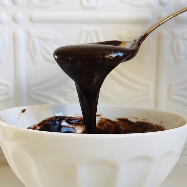 Paleo hot fudge sauce dripping off a spoon.