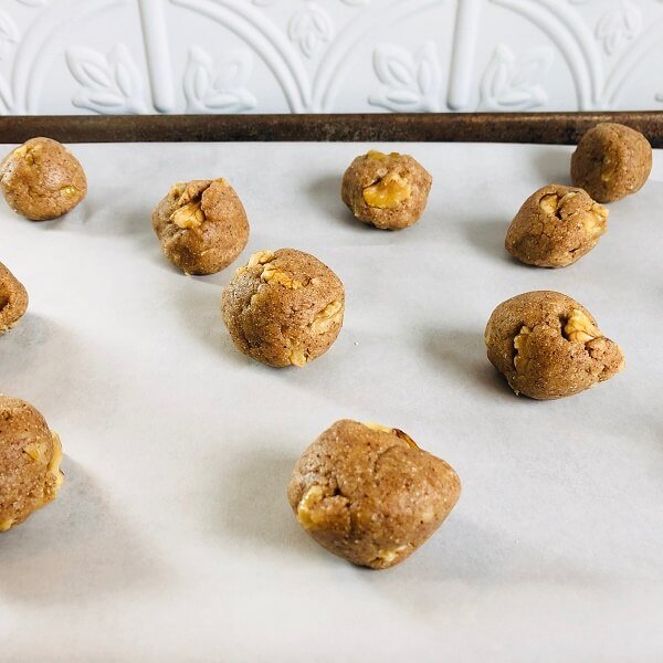 Raw cookie dough rolled in balls on a baking tray.