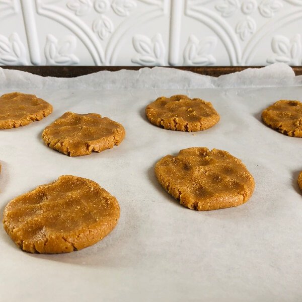 Flattened flourless cookie dough on a baking tray.