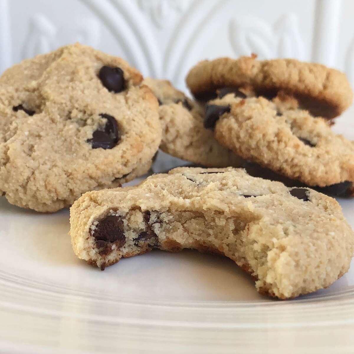 A pile of chocolate chip cookies with a bite missing from one.