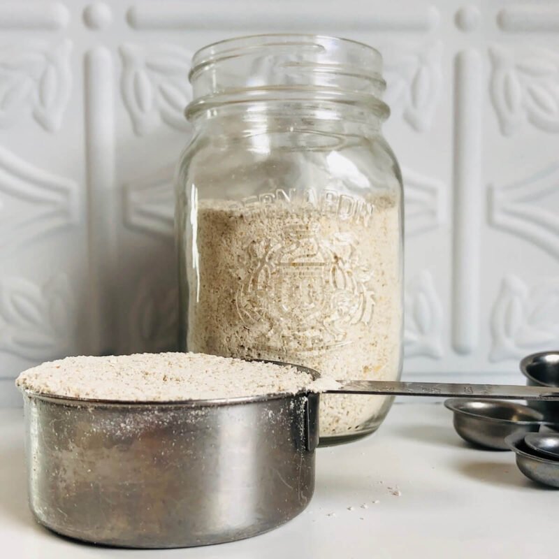 A measuring cup and mason jar filled with oat flour.