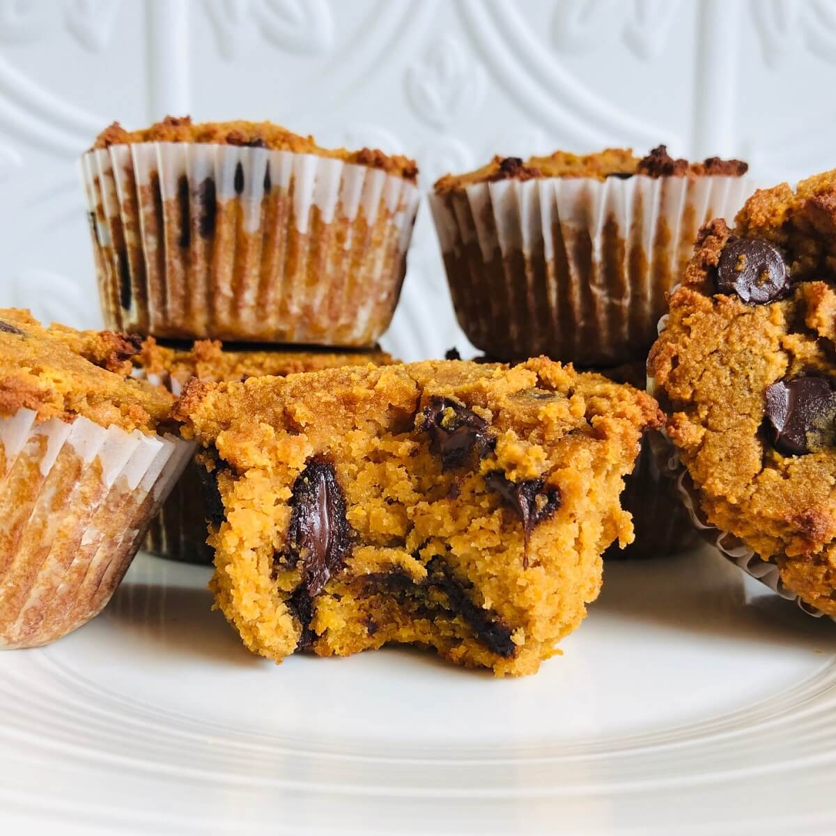 Seven paleo sweet potato muffins arranged on a white plate.