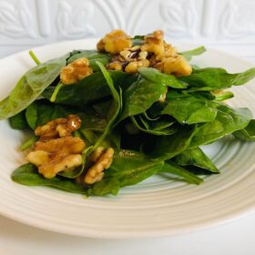 A white plate full of salad with maple vinaigrette.