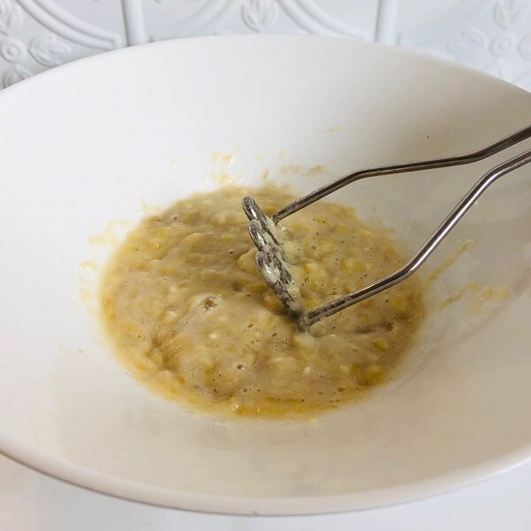 A bowl of mashed bananas against a white background.