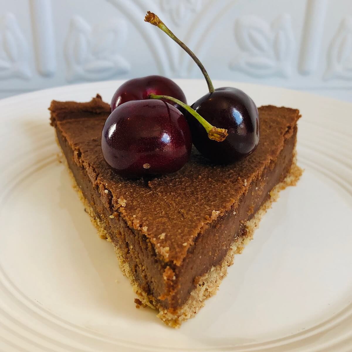 A slice of cheesecake with three cherries on top.
