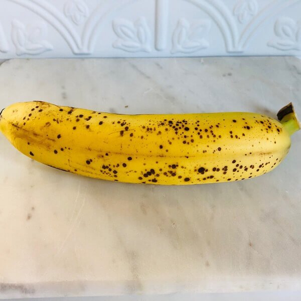 A ripe banana on a marble cutting board.