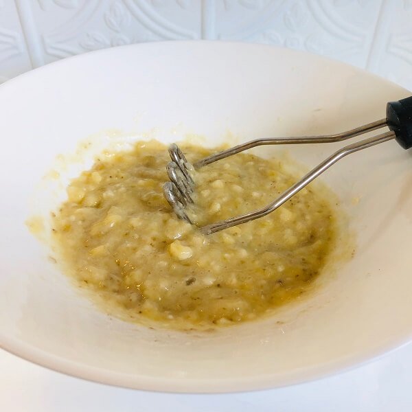 Mashed banana in a large white bowl.