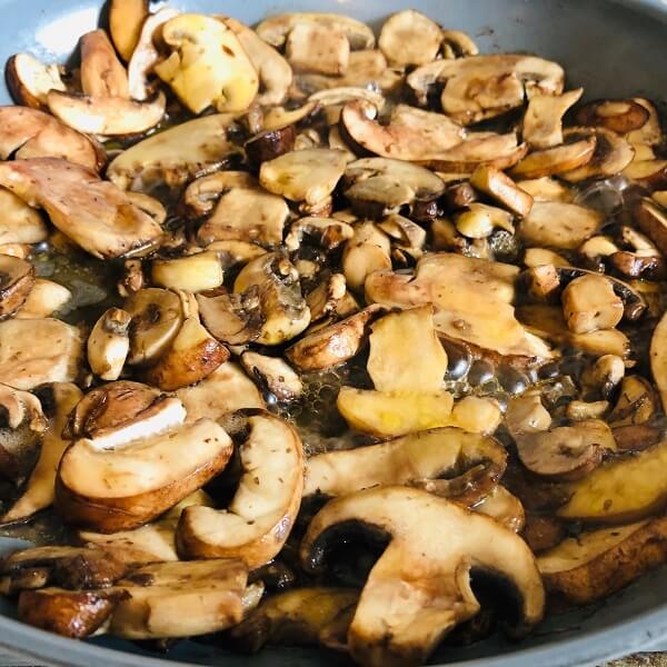 Mushrooms cooking in a frying pan.