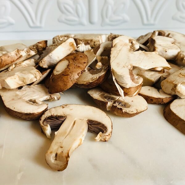 Mushrooms sliced on a cutting board.