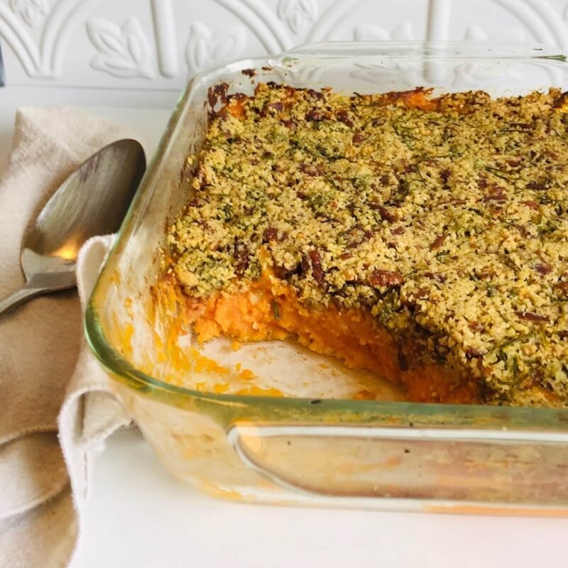 Sweet potato casserole in a glass dish with a scoop missing.