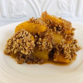 A serving of peach crisp on a white plate.