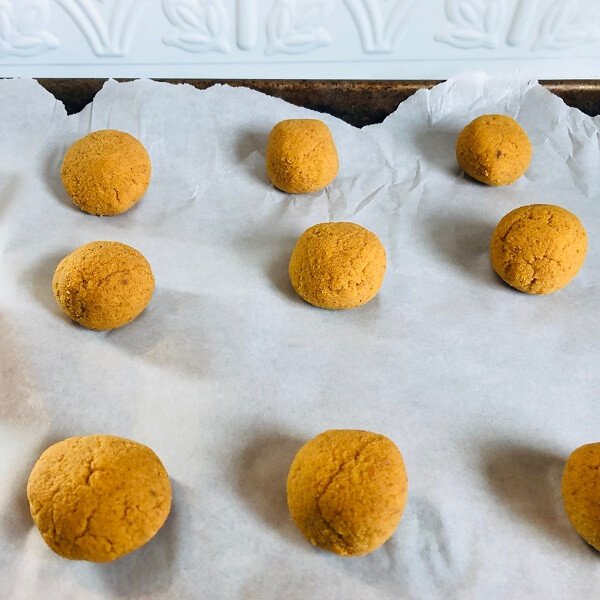 Raw cookie dough balls on a baking sheet pan.