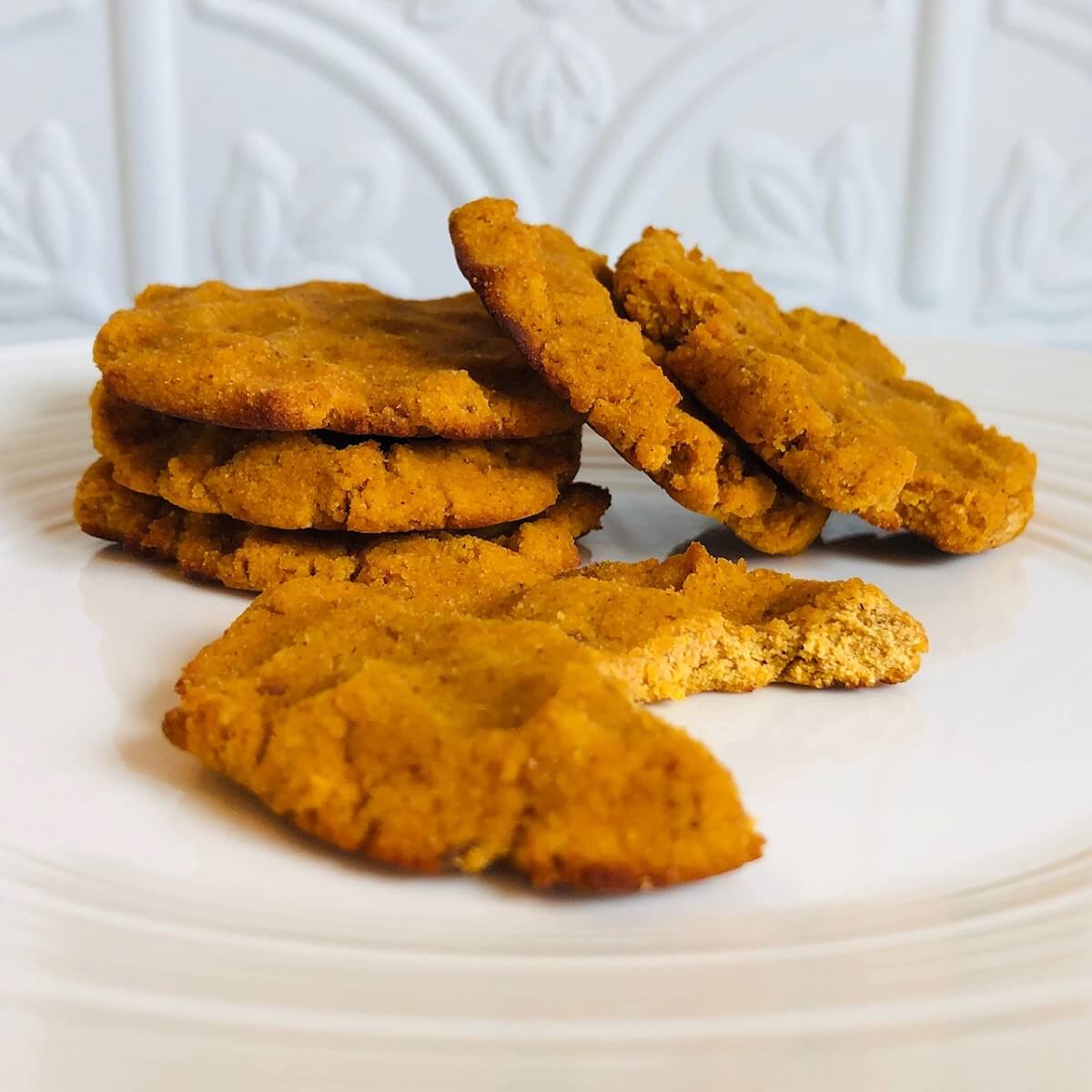 Six coconut flour pumpkin cookies displayed on a plate.