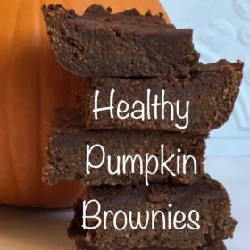 Brownies stacked on a white countertop in front of a pumpkin.