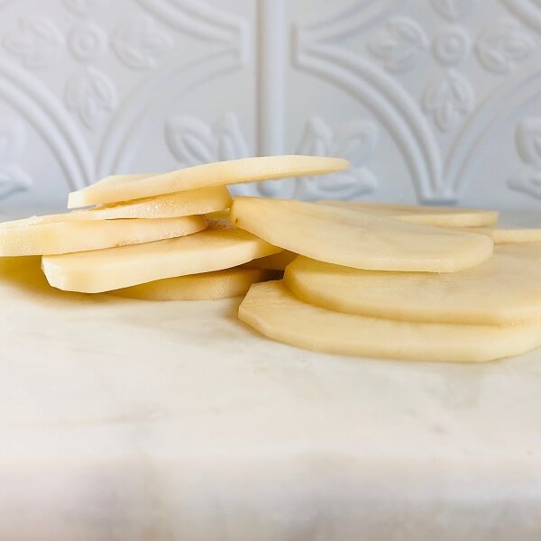 Thinly sliced potatoes on a marble cutting board.