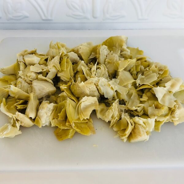 Chopped artichokes on a white cutting board.