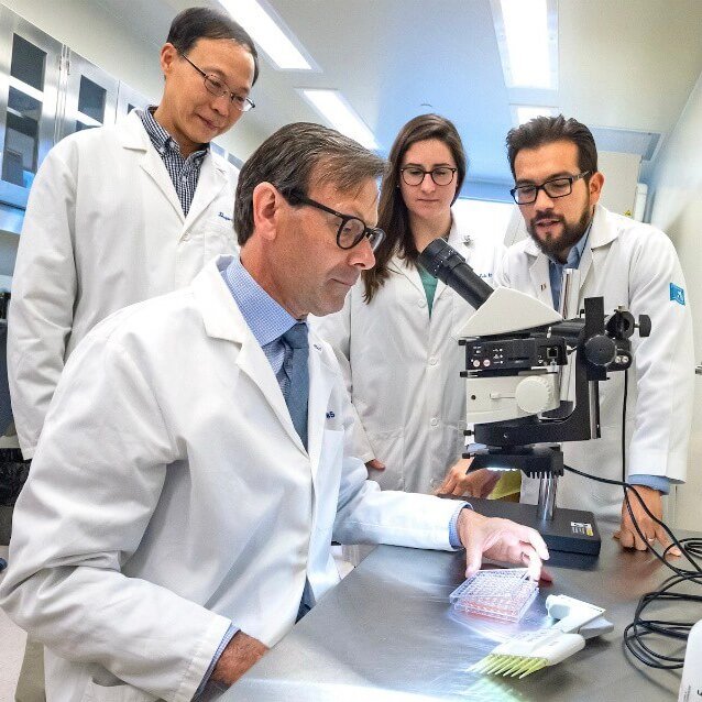 Four scientists gathered around a microscope.