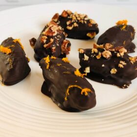 Chocolate coated dates on a white plate.