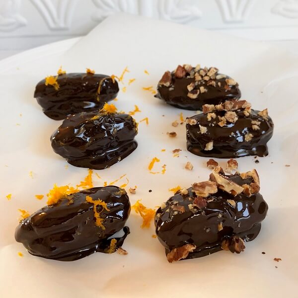 Chocolate dates drying on a piece of parchment paper.
