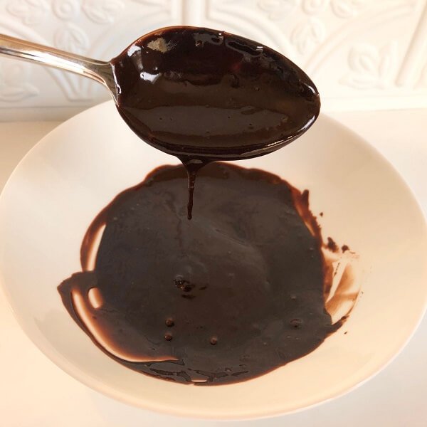 Chocolate glaze dripping off of a stainless steel spoon.