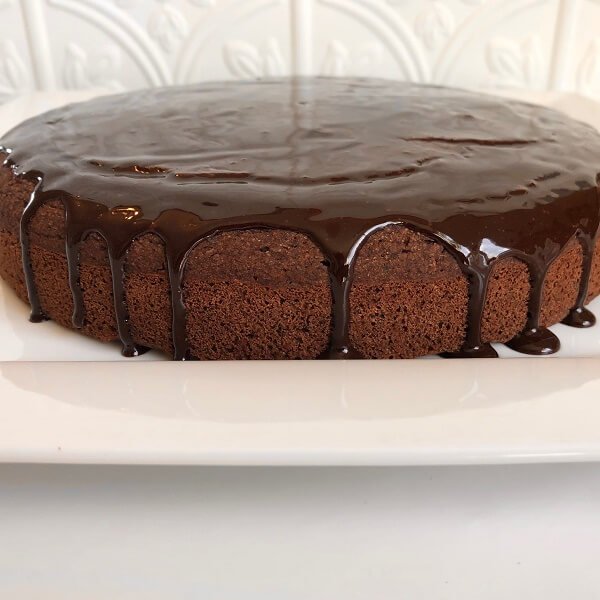 A chocolate glazed cake on a white platter.