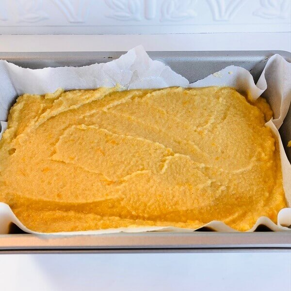 Raw orange cake batter in a loaf pan.