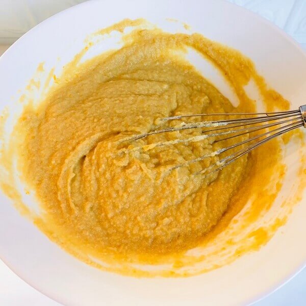 Cake batter in a white bowl being whisked.