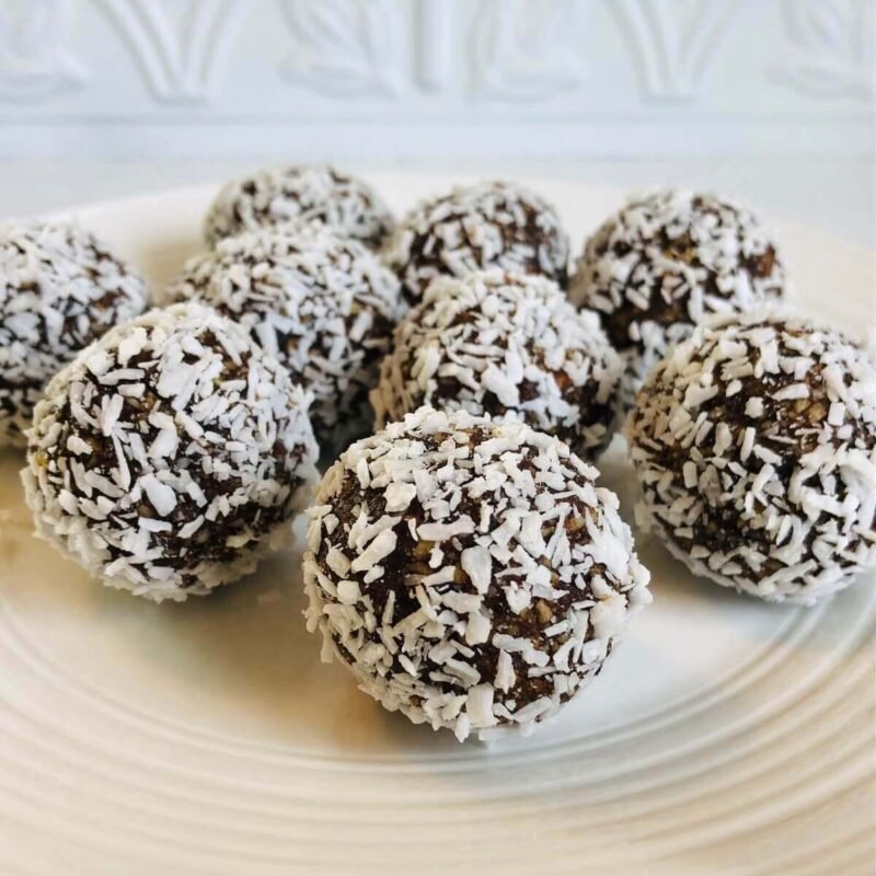 Nine coconut balls on a white plate.