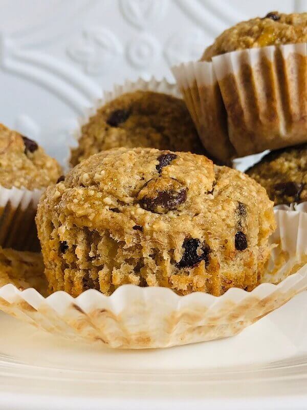 Five muffins arranged on a white plate.