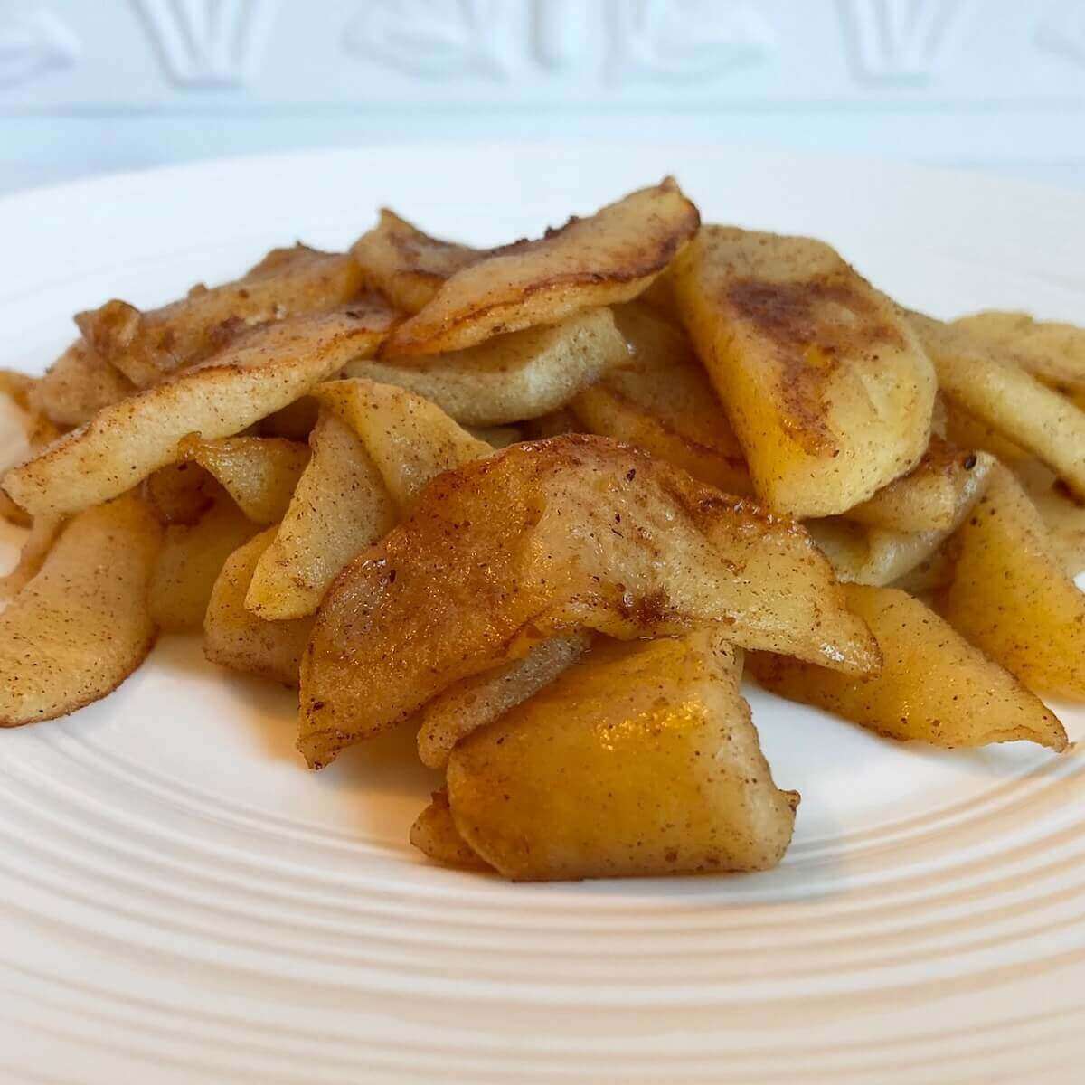 Sauteed cinnamon apples on a white plate.