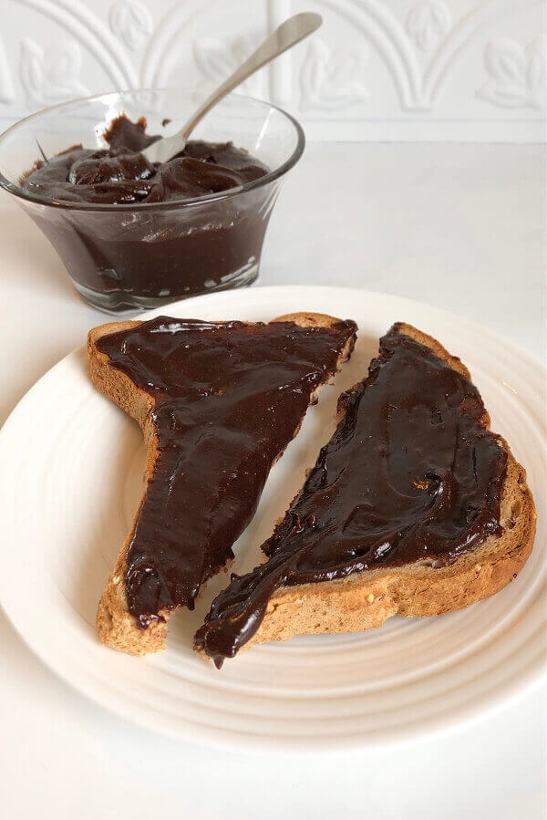 Toast next to a glass dish of chocolate spread.