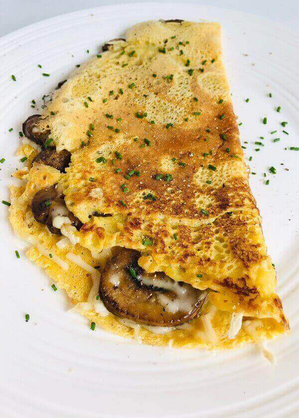 An omelette stuffed with mushrooms on a plate.