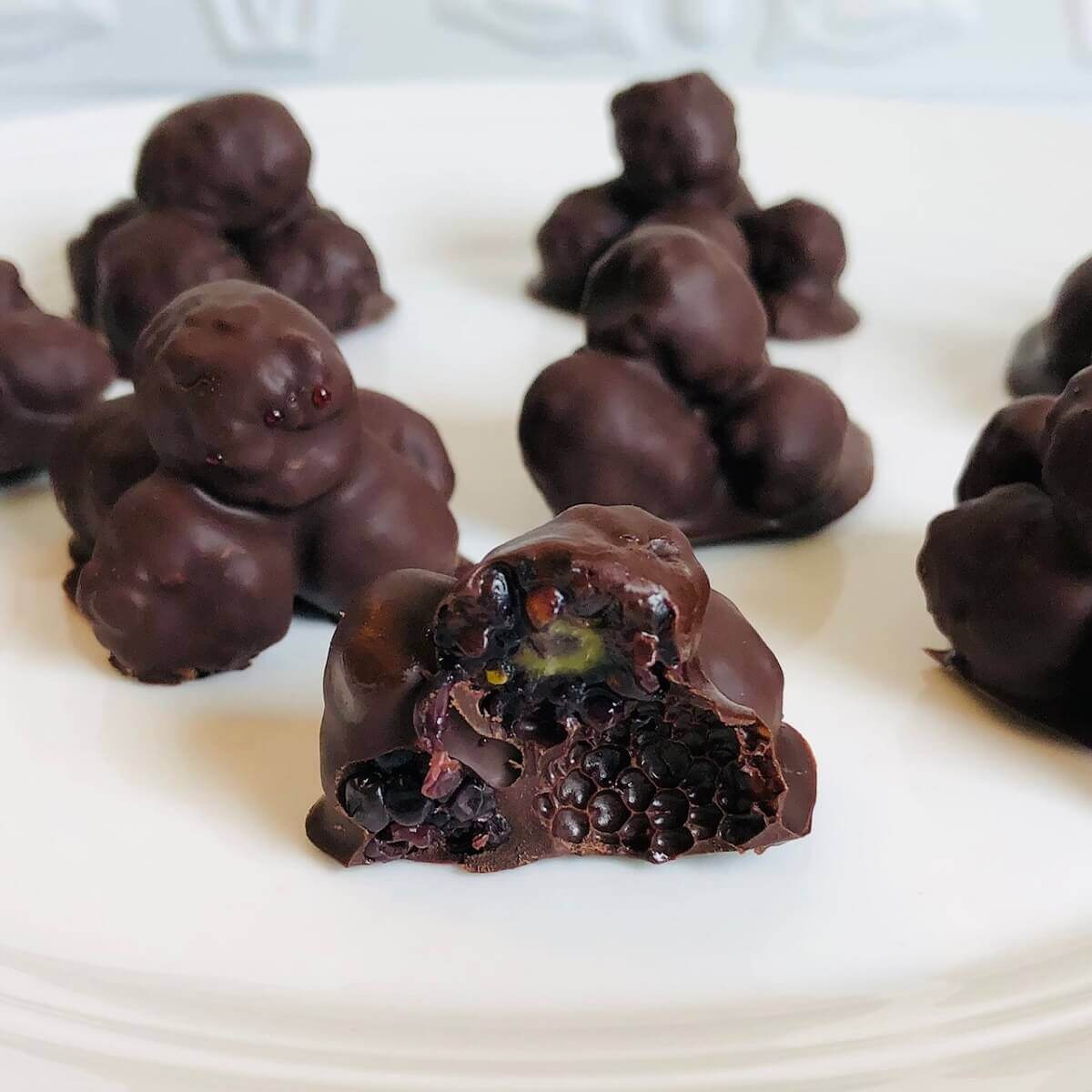 Chocolate covered blackberries on a white plate.