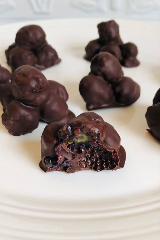 Chocolate dipped blackberries on a plate.