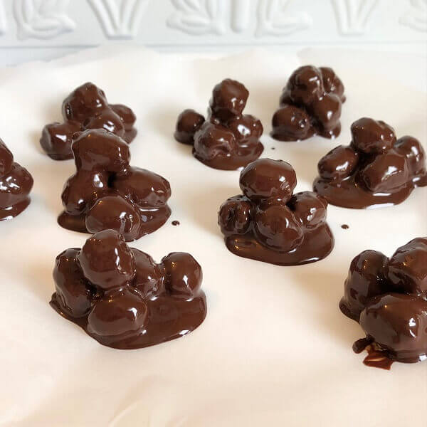 Berries dipped in melted chocolate drying on a plate.